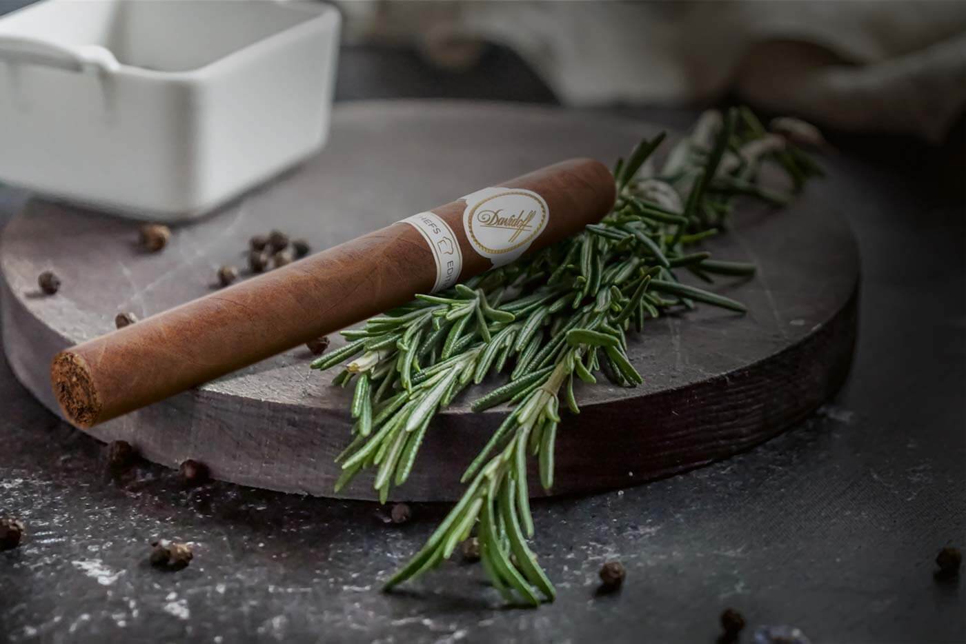 Davidoff Chefs Edition 2021 Churchill Cigar on a chopping board with rosemary and pepper.