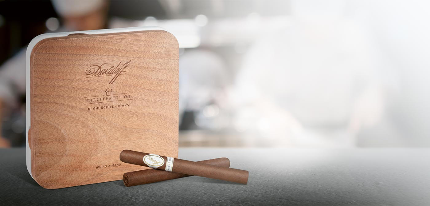Two Davidoff Chefs Edition 2021 Cigars next to its box-packaging made of wooden lid and ceramic base